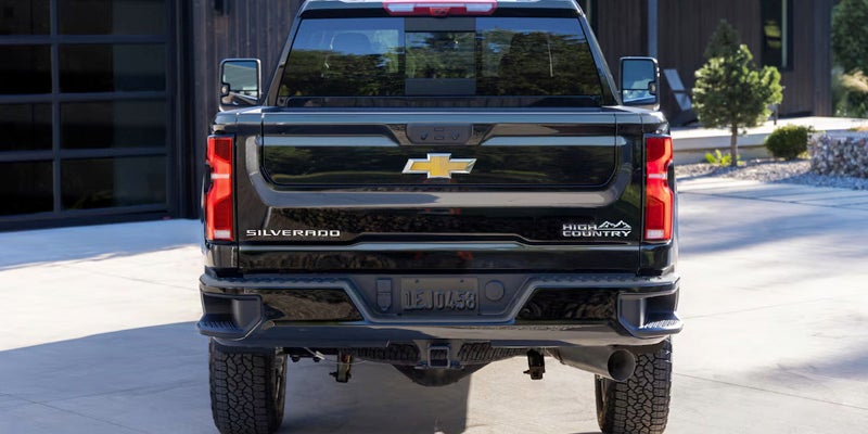 The rear view of a black Chevrolet Silverado truck, showcasing its sleek design and distinctive tailgate features.