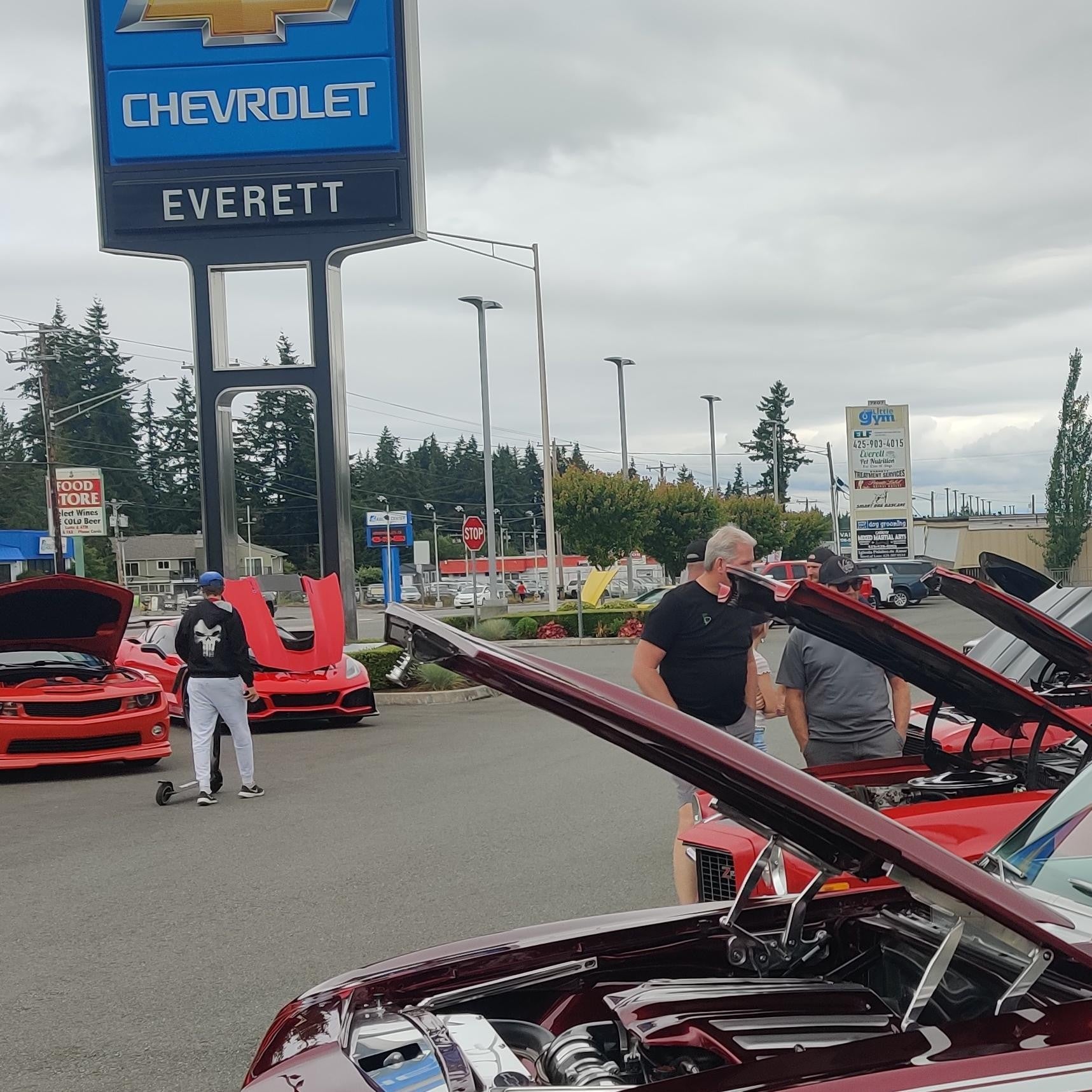 A diverse group of people admiring various cars on display at a vibrant car show event.