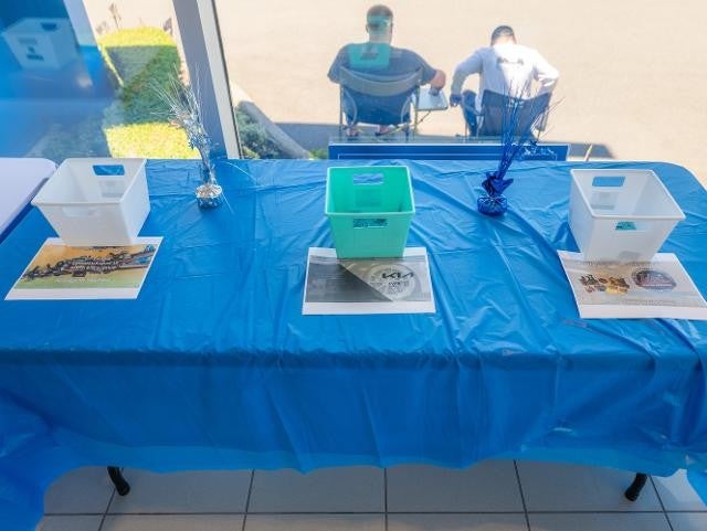A table covered with a blue tablecloth, featuring several blue plastic containers arranged on top.