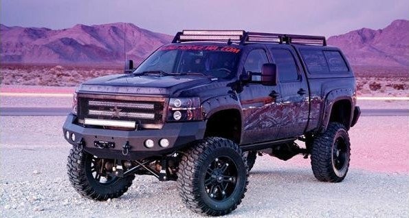 A black truck equipped with a lift, showcasing its robust design and elevated stance.