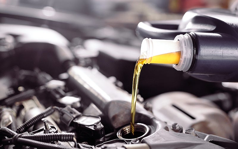 A person carefully pours oil into the engine of a car, ensuring proper maintenance and performance.